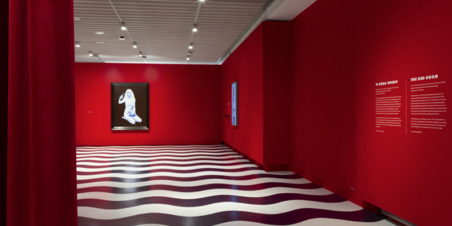 Gallery space with black and white floor detailing and red walls.