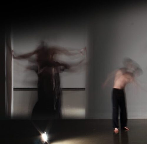 Blurred figures dancing in an empty gallery space.